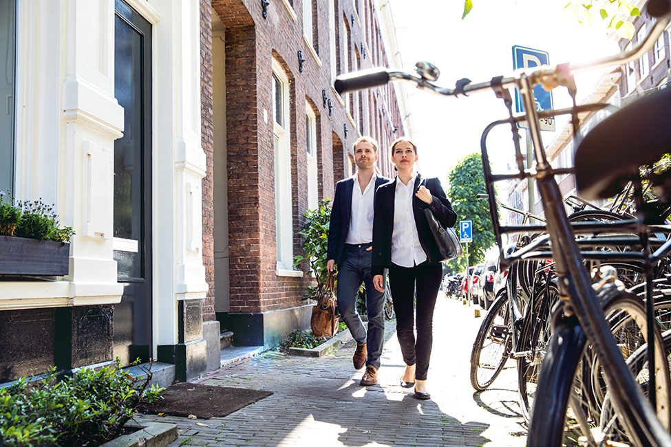 Two-people-in-work-attire-walking-down-a-sidewalk.
